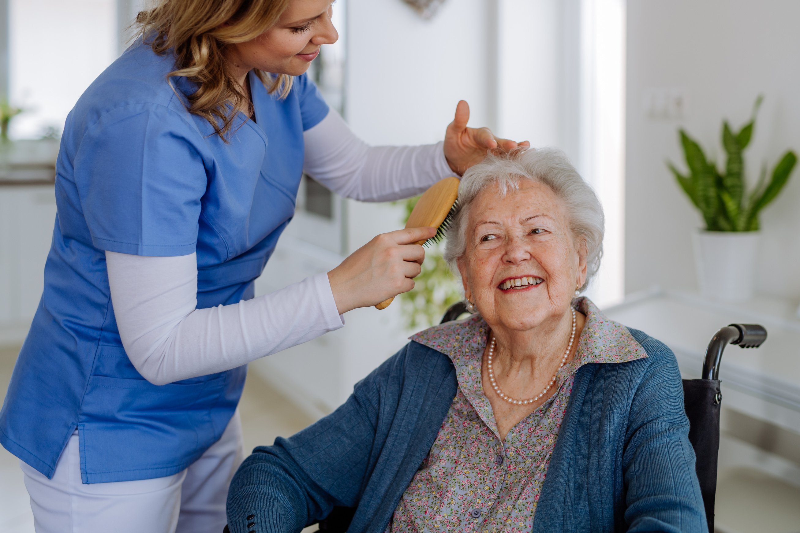 Caregiver Brushing Hair of Elderly Woman