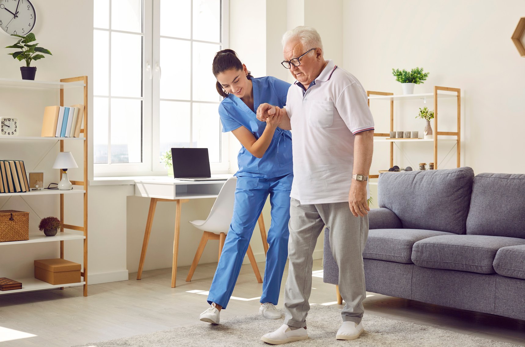 Nurse in Assisted Living Facility Holding Elderly Patient by Hand and Helping Him Walk